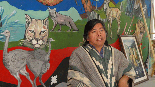 Jorge Nahuel in front of a large painting of a field with several animals