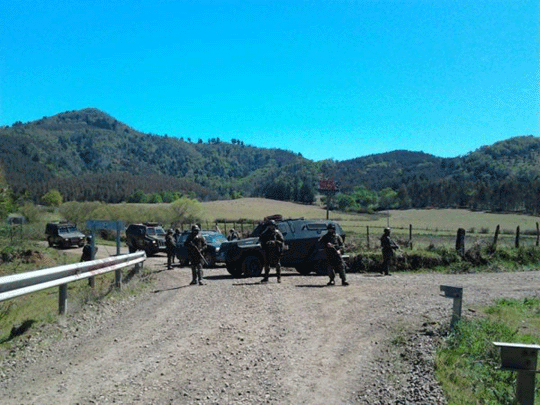 Paramilitaries and their vehicles at a crossroads on a rural gravel road